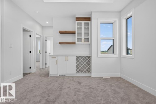 Integrated custom cabinetry with glass-front uppers and a built-in wine rack - 101 Rosa Crescent, St. Albert, AB 