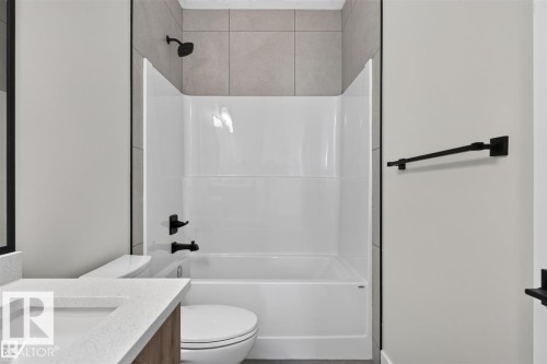 Shower-over-tub combination with tile surround, matte black fixtures, and a white vanity with an undermount sink and light-colored countertop - 101 Rosa Crescent, St. Albert, AB 