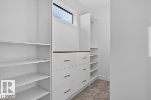 Built-in white cabinetry featuring multiple shelving units, six drawers with bronze-finish hardware, and a hanging rod - 101 Rosa Crescent, St. Albert, AB 