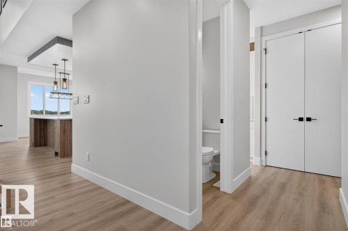 Wood-finish flooring throughout, modern white doors with black hardware, and an open concept layout with an exposed beam detail - 101 Rosa Crescent, St. Albert, AB 