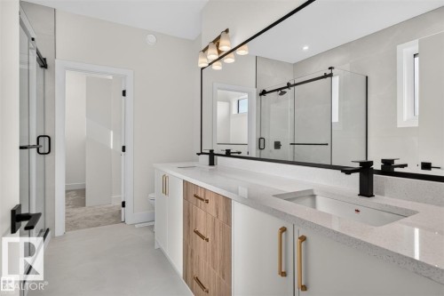 Dual vanity with quartz countertops, matte black faucets, and wood-finish cabinetry - 101 Rosa Crescent, St. Albert, AB 