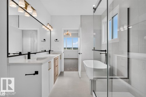 Dual vanity with quartz countertop, black finish fixtures, and a large frameless mirror - 101 Rosa Crescent, St. Albert, AB 