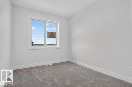 Neutral wall color, wall-to-wall carpeting, and a large window with white trim - 101 Rosa Crescent, St. Albert, AB 