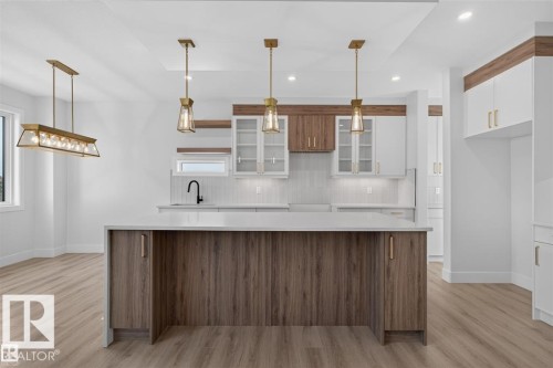 Kitchen with two-tone cabinetry, a central island, and wood-finish flooring - 101 Rosa Crescent, St. Albert, AB 
