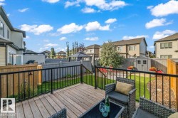 Wood-finish deck with black metal railing, leading to a landscaped yard with artificial turf and a storage shed - 