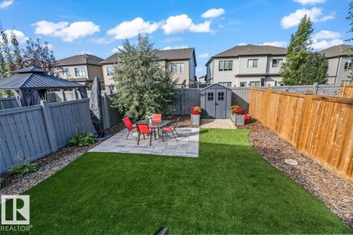 Landscaped yard with artificial turf, paver patio, wood fencing, and garden shed - 75 Garneau Gate, Spruce Grove, AB 