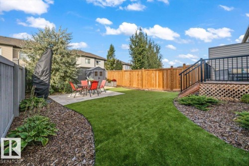 Expansive backyard featuring a patio, artificial turf, wood fence, privacy fence, and an elevated deck with black railings - 75 Garneau Gate, Spruce Grove, AB 