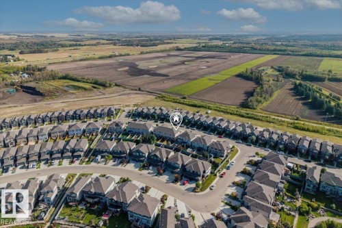 Aerial perspective showcasing a residential community with contemporary architecture, organized street layouts, and proximity to expansive agricultural fields - 75 Garneau Gate, Spruce Grove, AB 