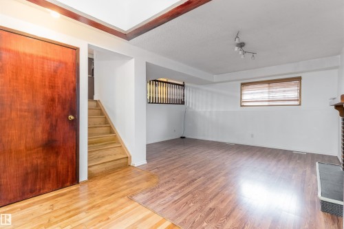 Wood-finish flooring throughout, with a built-in fireplace featuring a decorative wood mantel - 18739 72 Avenue Nw, Edmonton, AB 