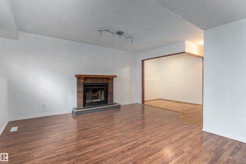 Brick fireplace with a wood mantel and stone hearth - 18739 72 Avenue Nw, Edmonton, AB 