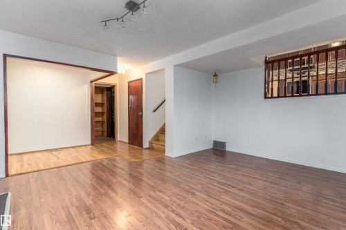 Wood-finish flooring throughout, white painted walls, track lighting fixture, and a built-in shelving unit - 18739 72 Avenue Nw, Edmonton, AB 