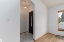 Archway entrance with a decorative hanging light fixture, dark panel door with glass inserts, wood-finish flooring, and a window with blinds - 18739 72 Avenue Nw, Edmonton, AB 