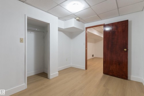 Recessed lighting, wood-finish flooring, white walls, built-in closet with hanging rod, and dark wood-paneled door - 18739 72 Avenue Nw, Edmonton, AB 