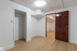 Recessed lighting, wood-finish flooring, white walls, built-in closet with hanging rod, and dark wood-paneled door - 