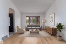 Light wood-finish flooring, bay window with blinds, arched doorway, white walls, dark-stained entry door with decorative glass - 18739 72 Avenue Nw, Edmonton, AB 