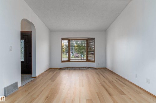 Light wood-finish flooring, a decorative front door with leaded glass, a bay window with wood-frame construction, and a gracefully arched doorway - 18739 72 Avenue Nw, Edmonton, AB 