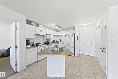 Kitchen featuring white cabinetry, light countertops, and a central island - #224 3425 19 St Nw, Edmonton, AB 