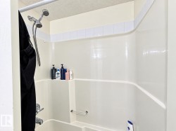 Integral shower/tub combination with a built-in shelf, grab bar, and chrome shower fixtures - 