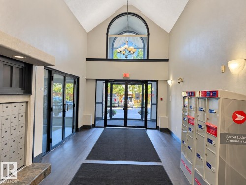 Two-story entryway with vaulted ceilings, an arched transom window, and wood-finish flooring - #224 3425 19 St Nw, Edmonton, AB 