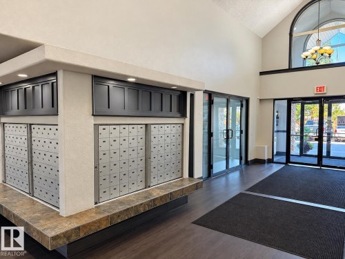 Vaulted ceiling with an arched window, wood-finish flooring, and multi-pane glass doors - #224 3425 19 St Nw, Edmonton, AB 