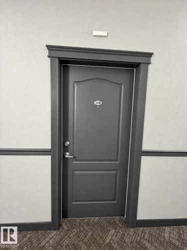 Molded panel door with dark trim, brushed nickel hardware, and textured wall finish - #224 3425 19 St Nw, Edmonton, AB 