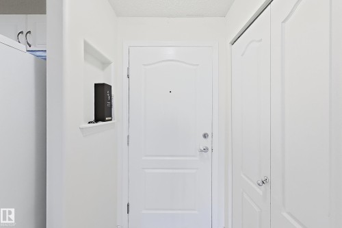 White entry door with decorative paneling and chrome hardware - #224 3425 19 St Nw, Edmonton, AB 