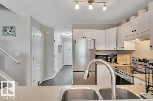 Kitchen featuring white cabinetry, stainless steel appliances, dual basin sink with gooseneck faucet, and light-toned countertops - 11448 169 Avenue Nw, Edmonton, AB 