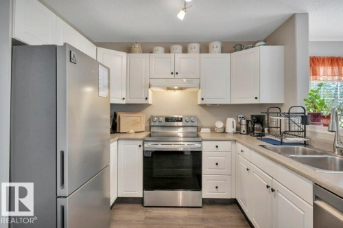 Galley kitchen with white shaker-style cabinetry, a stainless steel electric range, and a double basin sink - 11448 169 Avenue Nw, Edmonton, AB 