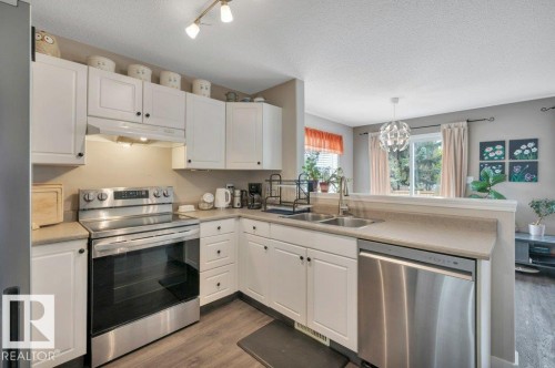 Kitchen featuring white cabinetry, stainless steel appliances, vinyl plank flooring, and track lighting - 11448 169 Avenue Nw, Edmonton, AB 