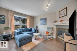 Wood-finish vinyl plank flooring, a prominent window, a built-in fireplace with a stone surround, and a ceiling-mounted track light fixture - 