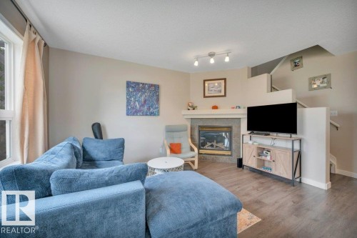 Living area featuring wood-finish flooring, a gas fireplace with a mantel, and track lighting - 11448 169 Avenue Nw, Edmonton, AB 