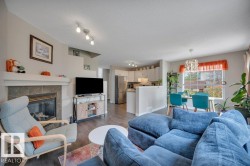 Open-concept living area featuring a tile-surround, gas fireplace with a mantel, wood-finish flooring, and track lighting - 