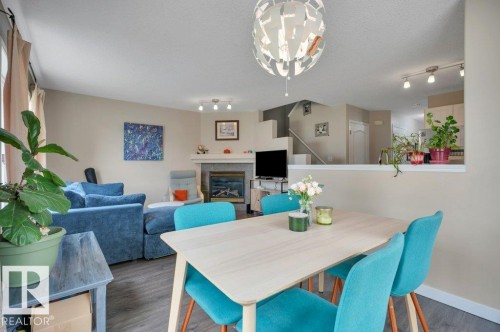 Open-concept living area featuring vinyl plank flooring, a contemporary, gasfireplace with a tile surround, and a modern chandelier - 11448 169 Avenue Nw, Edmonton, AB 