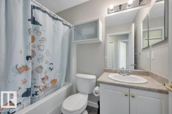 Main Bath. 4-piece. White porcelain tub, white vanity with integrated sink, laminate countertop, mirrored medicine cabinet, and wall-mounted light fixture - 
