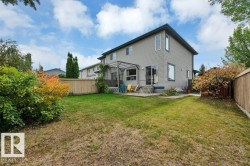 Expansive backyard featuring a manicured lawn, established shrubs, and a wood privacy fence - 