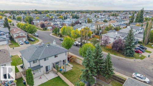 Gabled roofline, light-toned exterior, concrete patio, fenced yard, and mature trees - 11448 169 Avenue Nw, Edmonton, AB 