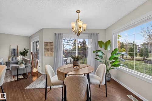 Dining area featuring dark wood-finish flooring, a multi-arm chandelier, and expansive windows with grid detailing - 7 Bremner, Fort Saskatchewan, AB 