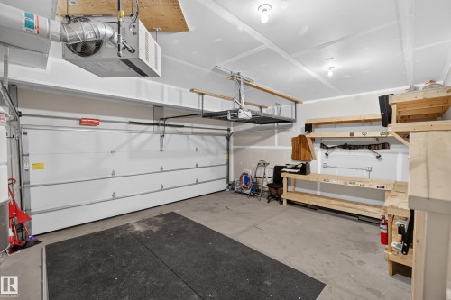 Garage featuring a finished ceiling, built-in wooden shelving, a wall-mounted workbench, and a ceiling-mounted climate control unit - 7 Bremner, Fort Saskatchewan, AB 