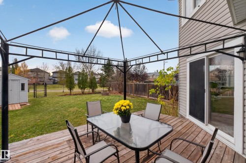 Wood-plank deck featuring a metal-frame gazebo, sliding glass door, and a detached storage shed set in a fenced yard - 7 Bremner, Fort Saskatchewan, AB 