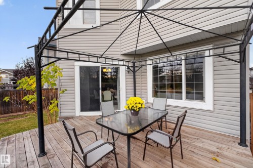 Exterior deck featuring horizontal wood decking, a metal-framed gazebo, sliding glass doors, and light-toned horizontal siding - 7 Bremner, Fort Saskatchewan, AB 