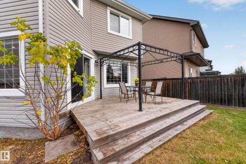 Rear exterior featuring a wood deck with tiered stairs, a metal gazebo frame, horizontal siding, and a fenced backyard - 7 Bremner, Fort Saskatchewan, AB 