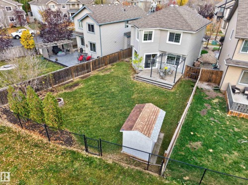 Fenced backyard featuring an elevated wood deck, detached storage shed, perimeter landscaping, and stone fire pit - 7 Bremner, Fort Saskatchewan, AB 