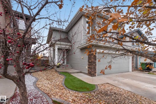 Two-story residence featuring grey horizontal siding, stone veneer accents, an attached two-car garage, covered entryway, and landscaped gravel beds with turf border - 7 Bremner, Fort Saskatchewan, AB 