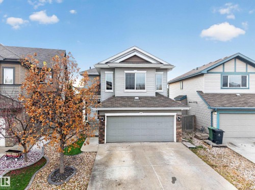 Two-story exterior featuring light-gray horizontal siding, stone-veneer accents, an asphalt shingle roof, and an attached two-car garage - 7 Bremner, Fort Saskatchewan, AB 