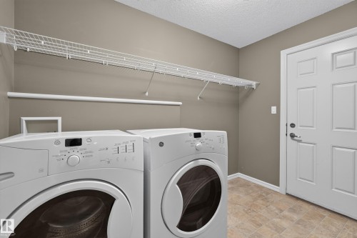 Laundry area featuring resilient tile flooring, full-length built-in wire shelving, and a six-panel door - 7 Bremner, Fort Saskatchewan, AB 