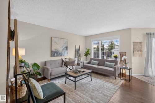 Living area featuring wood-finish flooring, a large window with grid muntins, and neutral wall paint - 7 Bremner, Fort Saskatchewan, AB 