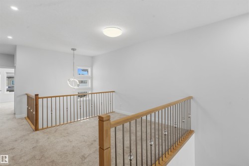Open interior space featuring light-colored carpet flooring, recessed lighting, and a modern circular pendant fixture - 2045 209A St Nw, Edmonton, AB 