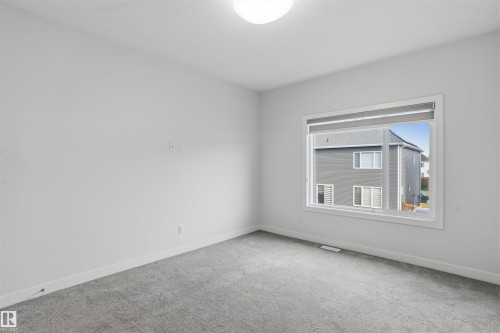 Neutral-toned interior space featuring neutral wall-to-wall carpeting, crisp white walls, and a large horizontal sliding window with an integrated roller shade - 2045 209A St Nw, Edmonton, AB 