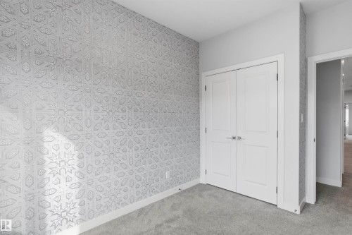 Geometric patterned wallpaper, double closet doors with brushed nickel hardware, and neutral wall-to-wall carpeting - 2045 209A St Nw, Edmonton, AB 