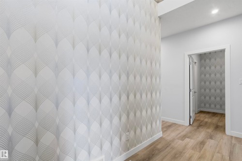 Interior space featuring geometric-patterned wall covering and wood-finish flooring - 2045 209A St Nw, Edmonton, AB 